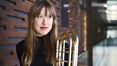 Henkilö Danna Nelson puhallinsoittimen kanssa käytävällä