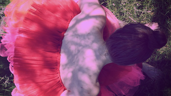 Kuvassa tummatukkainen henkilö punaisessa tyllihameessa kuvattuna ylhäältä.