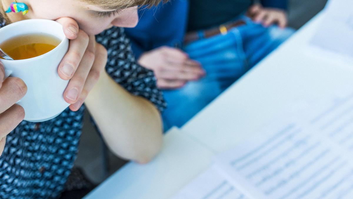 Nainen katsoo nuottikuvaa pidellen teekuppia