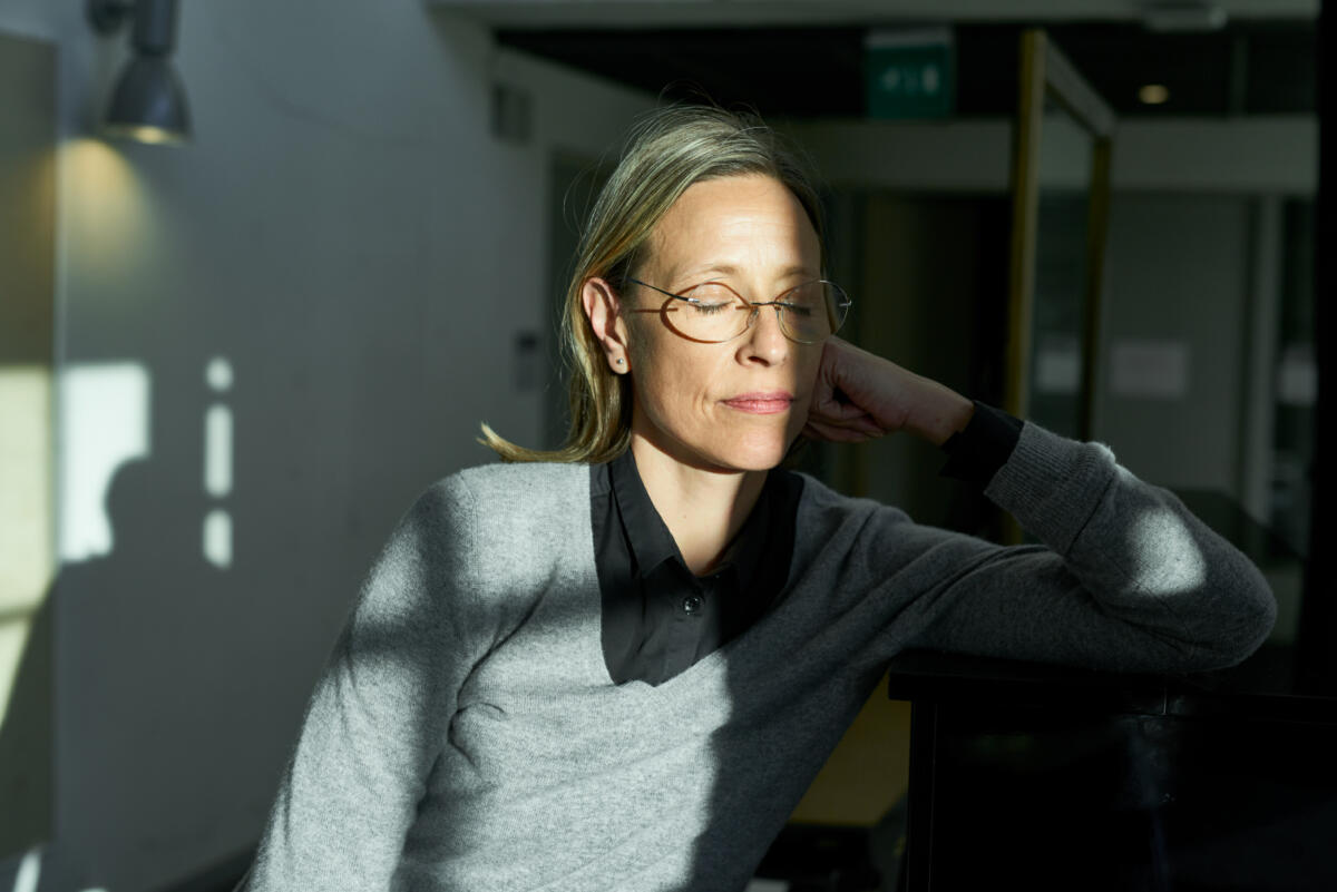 Leena Rouhiainen kuvattuna silmät kiinni auringon läikässä.