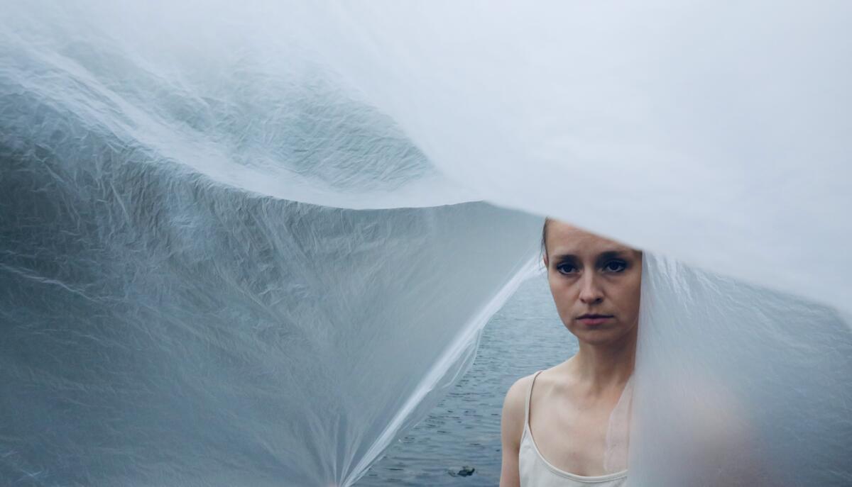 Kuvassa nainen meren äärellä.