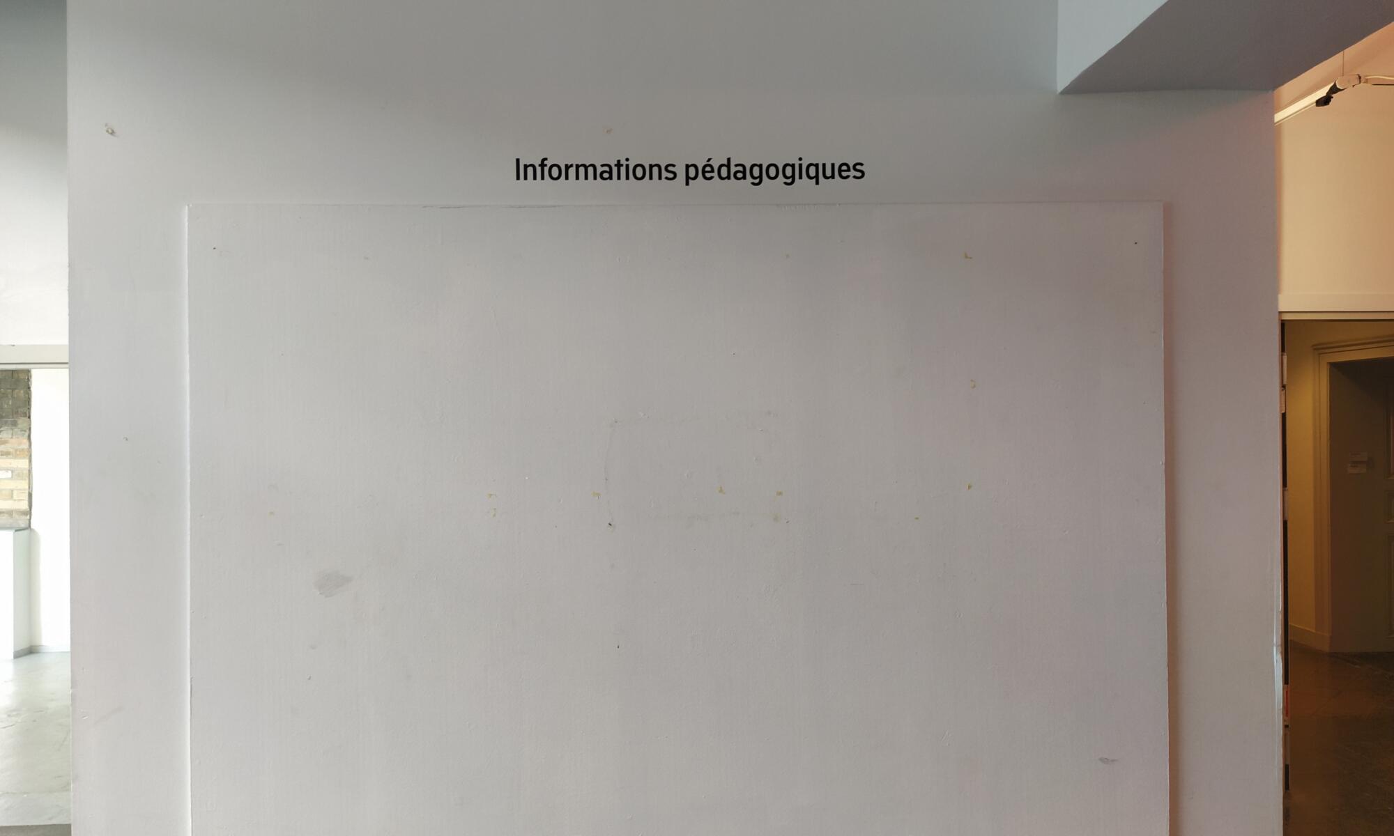 A blank white square on the wall with the words "information pedagoiques" on top of the square on the wall.