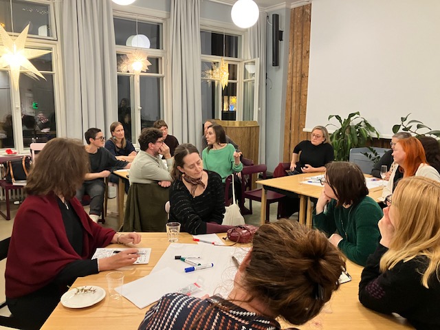 A photo of the previus workshop where people are discussing in small groups aroun tables in the Space of Science and Hope.