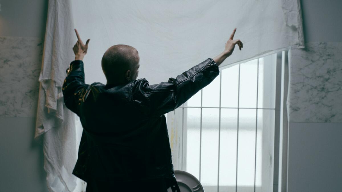 Takaapäin kuvattu henkilö, jolla molemmat kädet ilmassa.