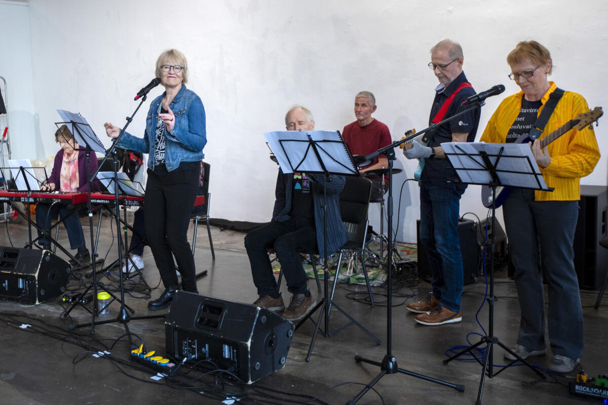 Seitsemän hengen bändi soittaa rock-bändinä. Mukana sekä mies- että naisolettettuja.